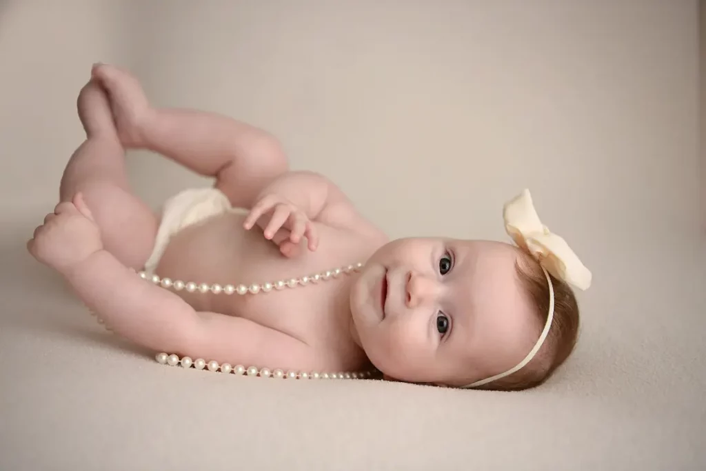 baby laying on back with pearl necklace